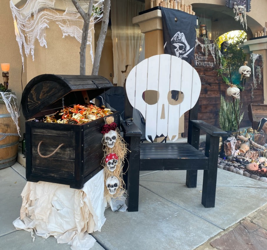 A chest of gold beside a large skull-backed chair